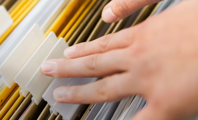 A hand rifling through a file drawer