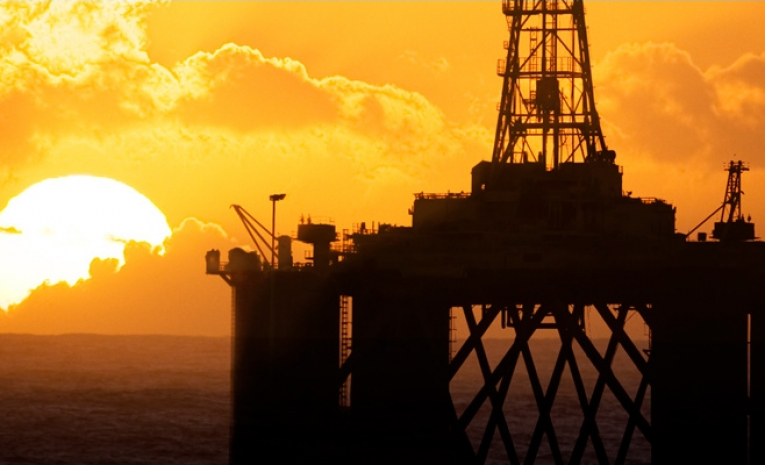 Oil rig in the ocean in front of a setting sun